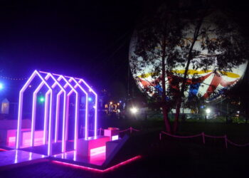 Allée de jardin faiblement éclairée la nuit par une lampe extérieure.